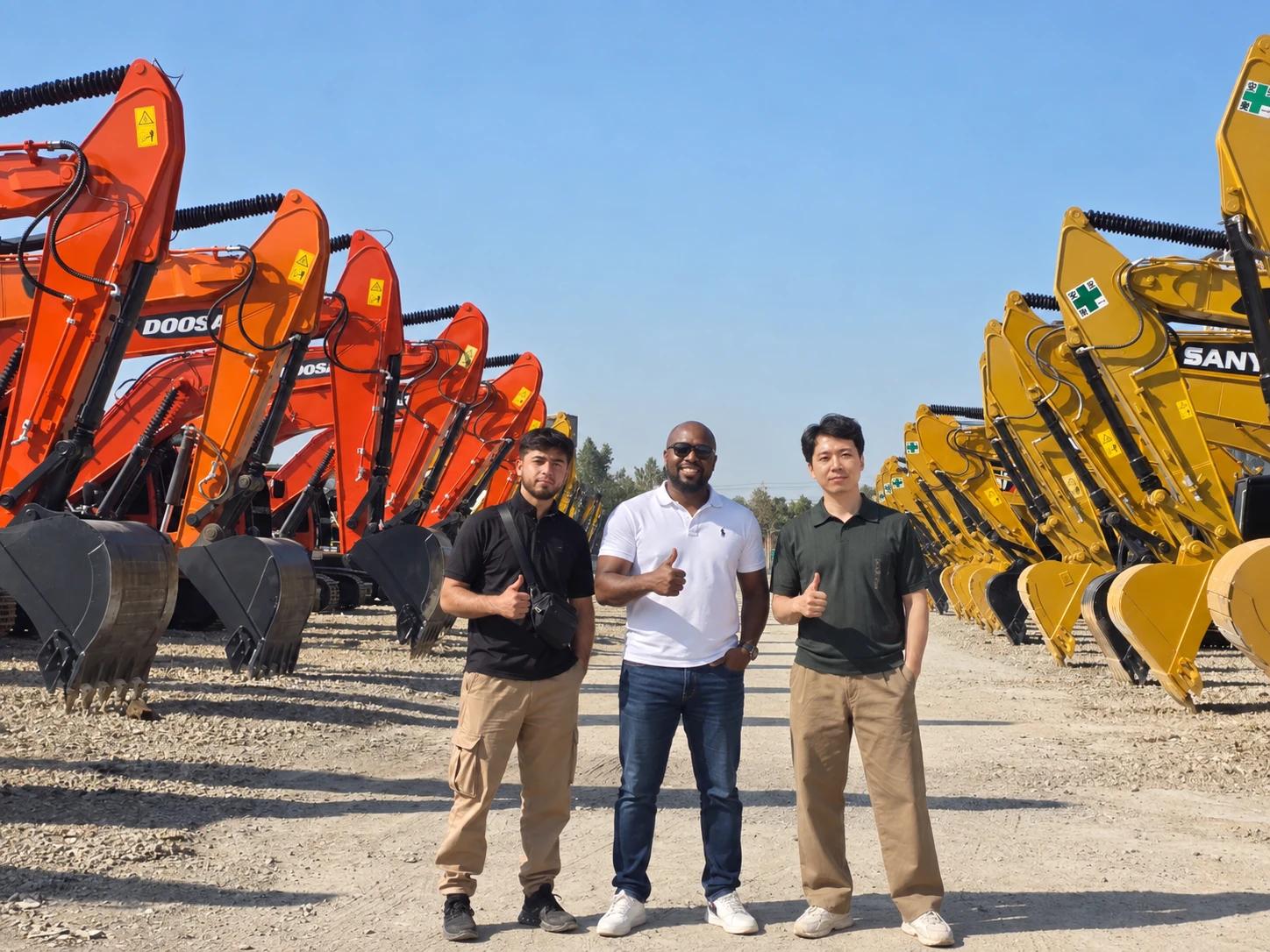 Three people standing between rows of excavators at an equipment yard